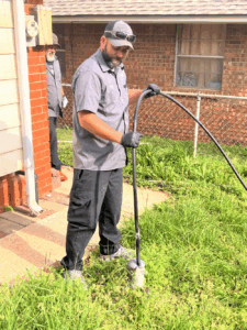 Amped Home Services technician using a hydro jetter to clear a grease clog, showcasing hydro jetting benefits.