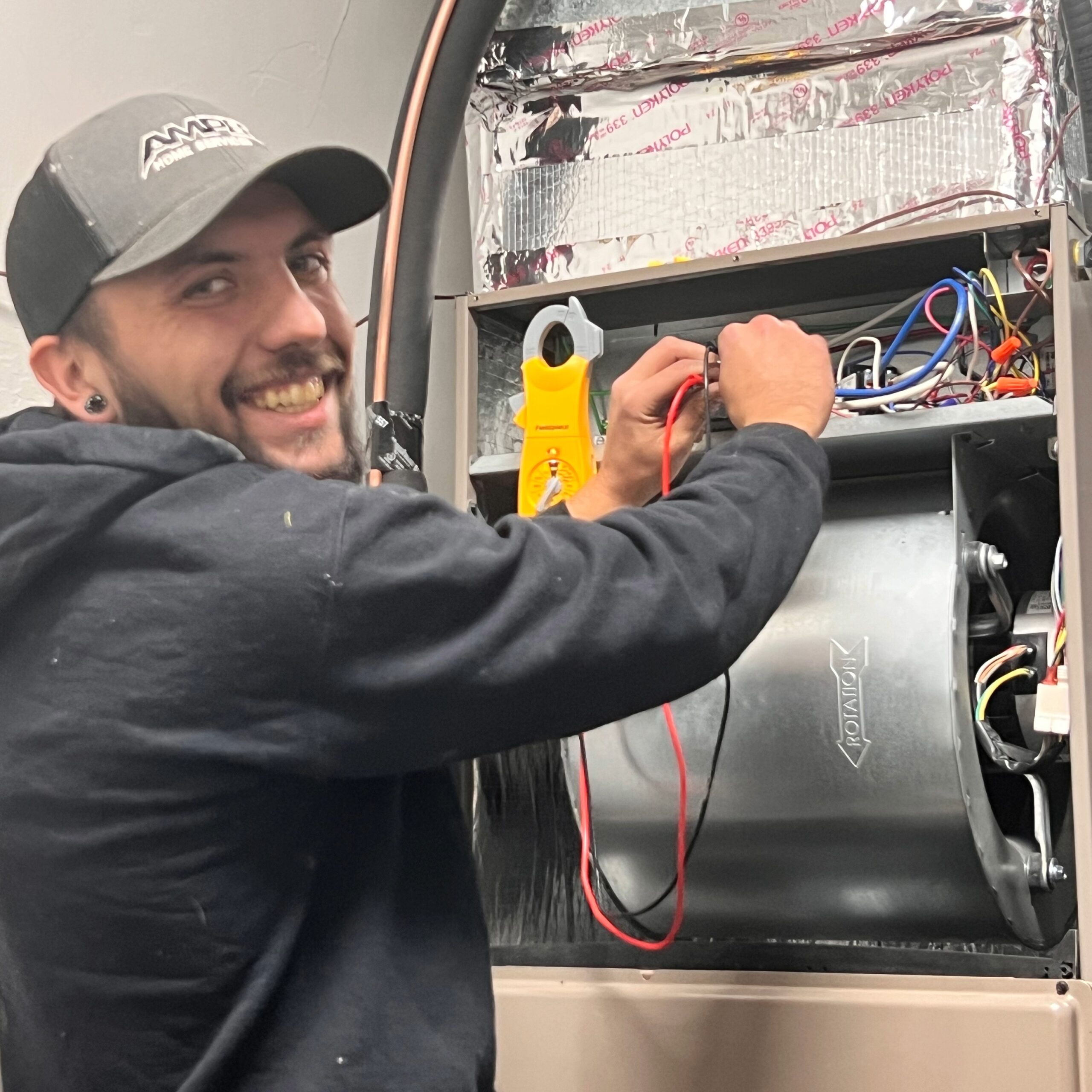 Amped HVAC technician testing wiring inside air handler in Oklahoma.