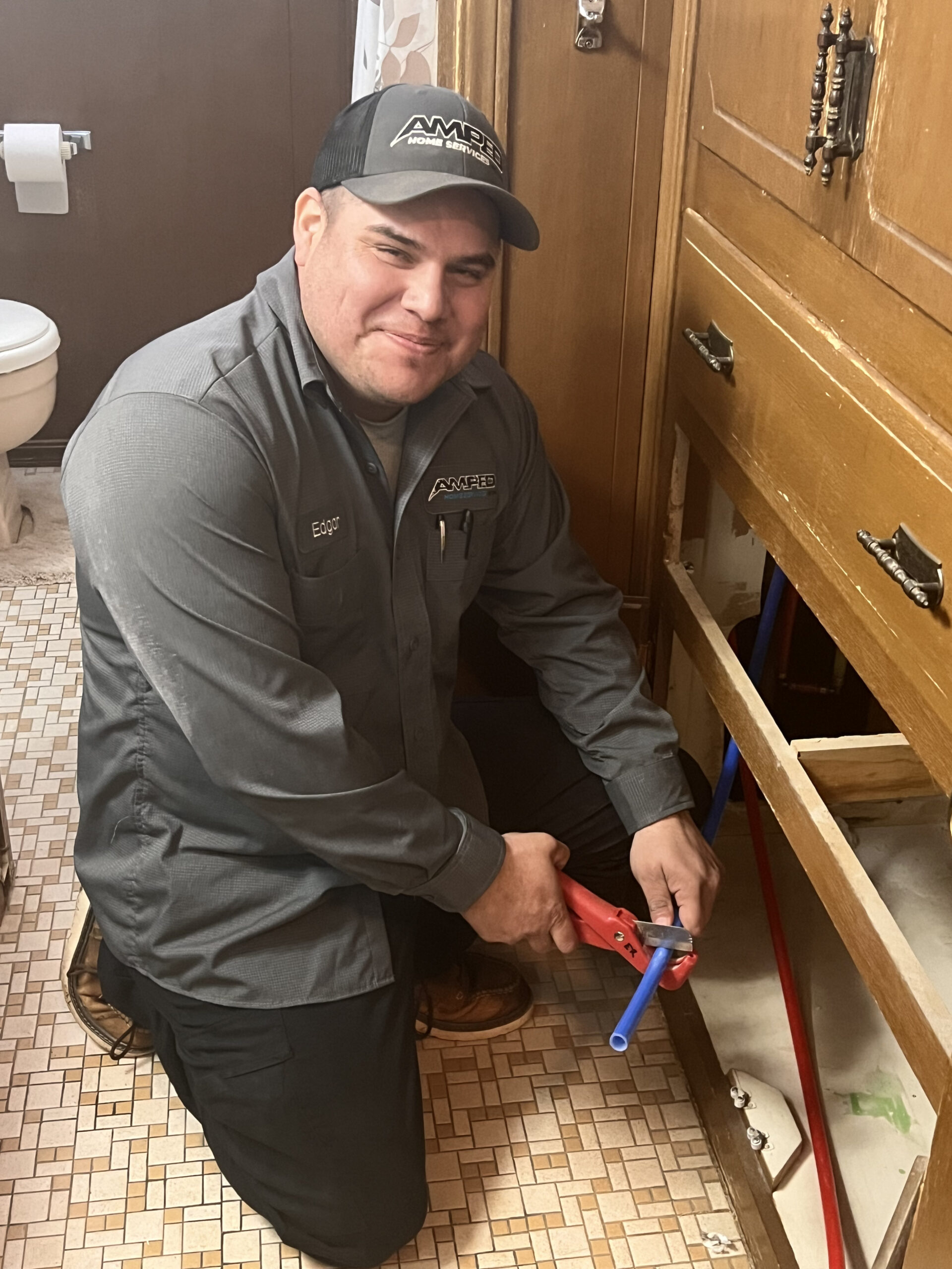 Amped plumber repairing pipes under a sink in Oklahoma.