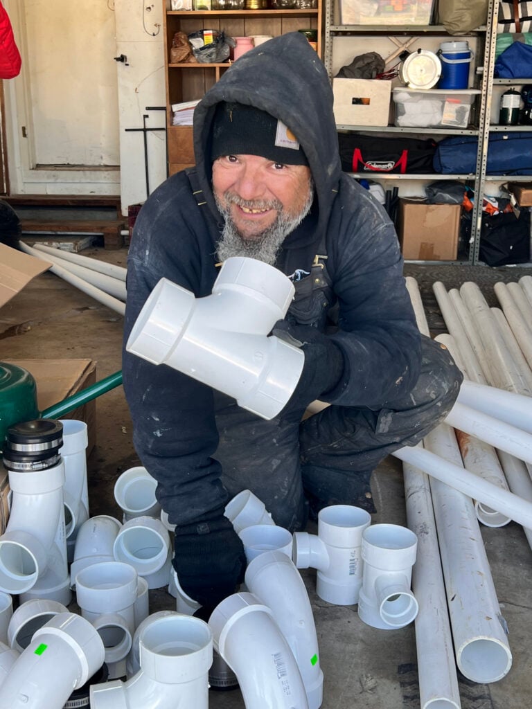 Amped plumber organizing PVC fittings for installation in Oklahoma.