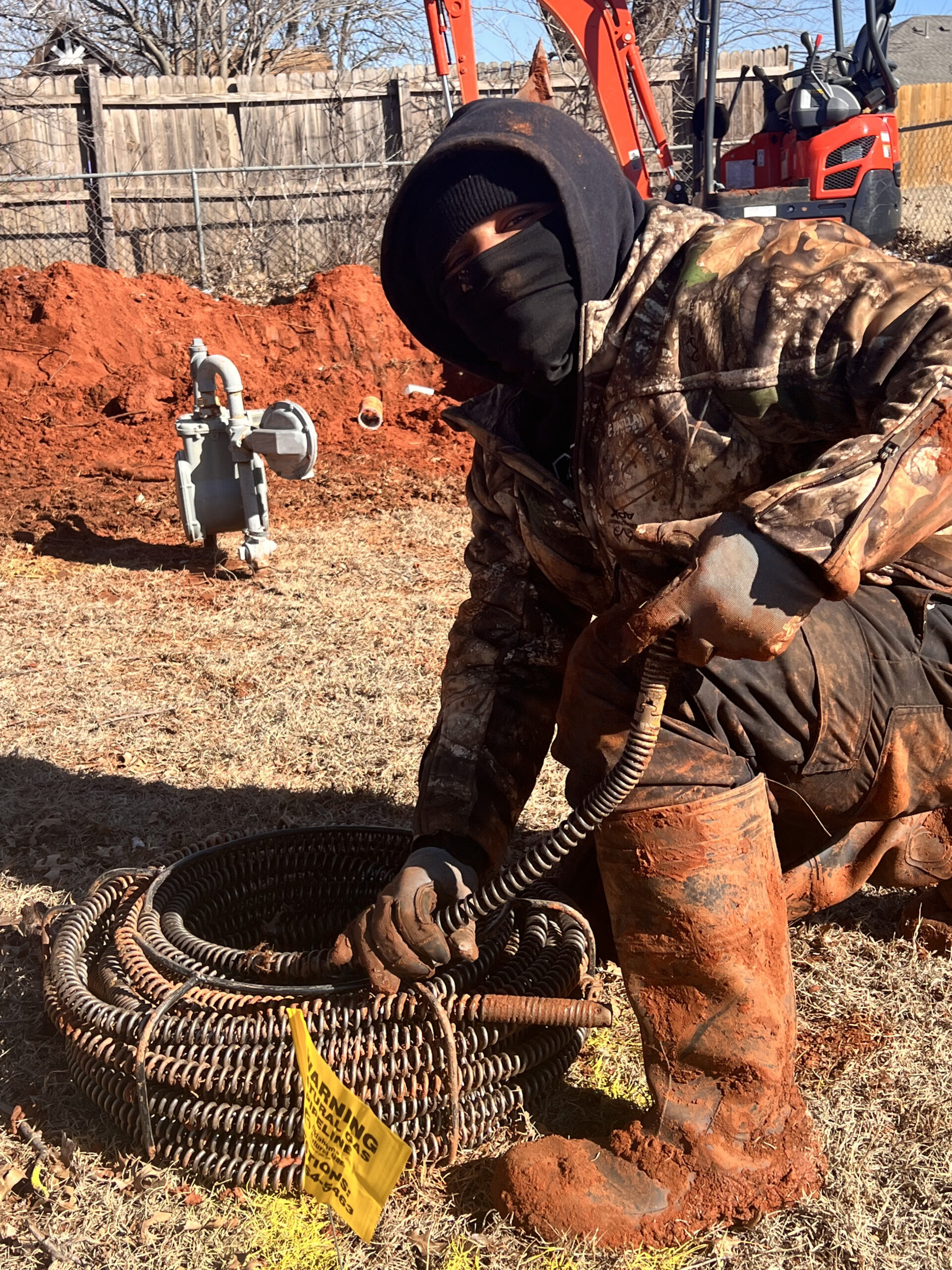Amped plumber operating drain snake for sewer cleaning in Oklahoma.