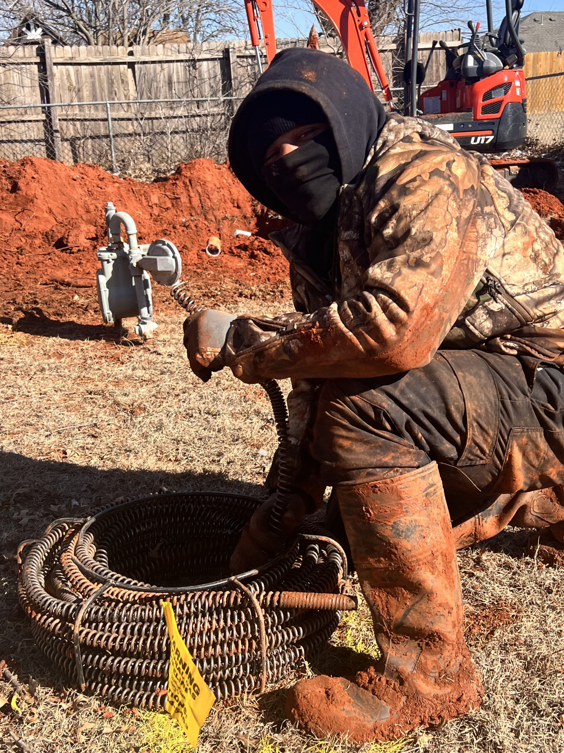 Amped plumber operating a drain snake for sewer cleaning in Oklahoma.