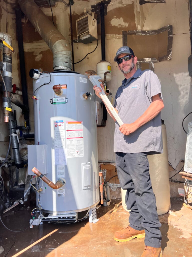 Amped plumber preparing water heater installation in Oklahoma.