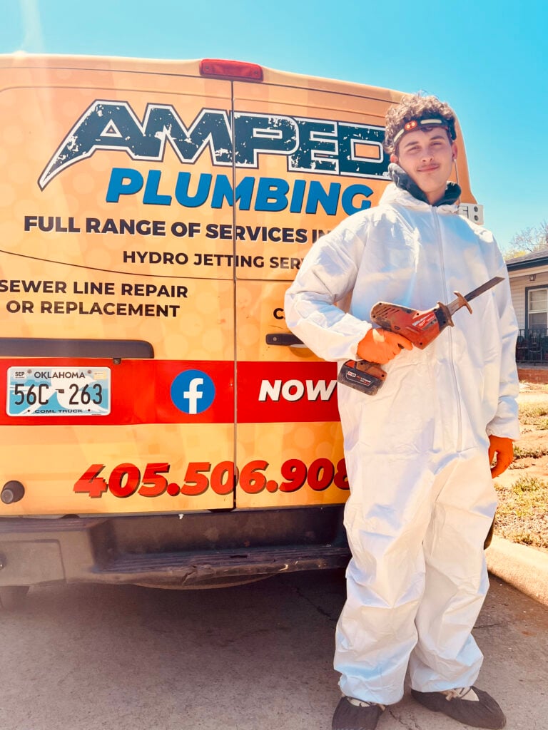 Amped plumber standing by service truck with tool in Oklahoma.
