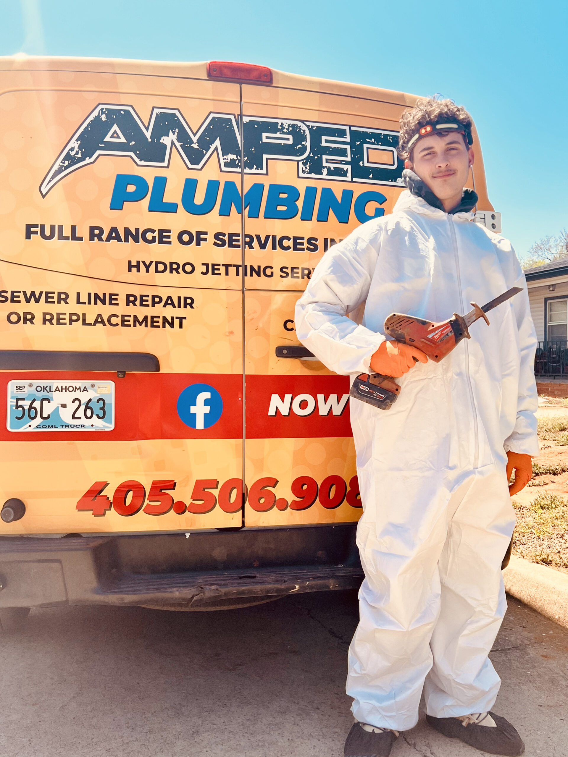 Amped plumber standing by service truck with tool in Oklahoma.