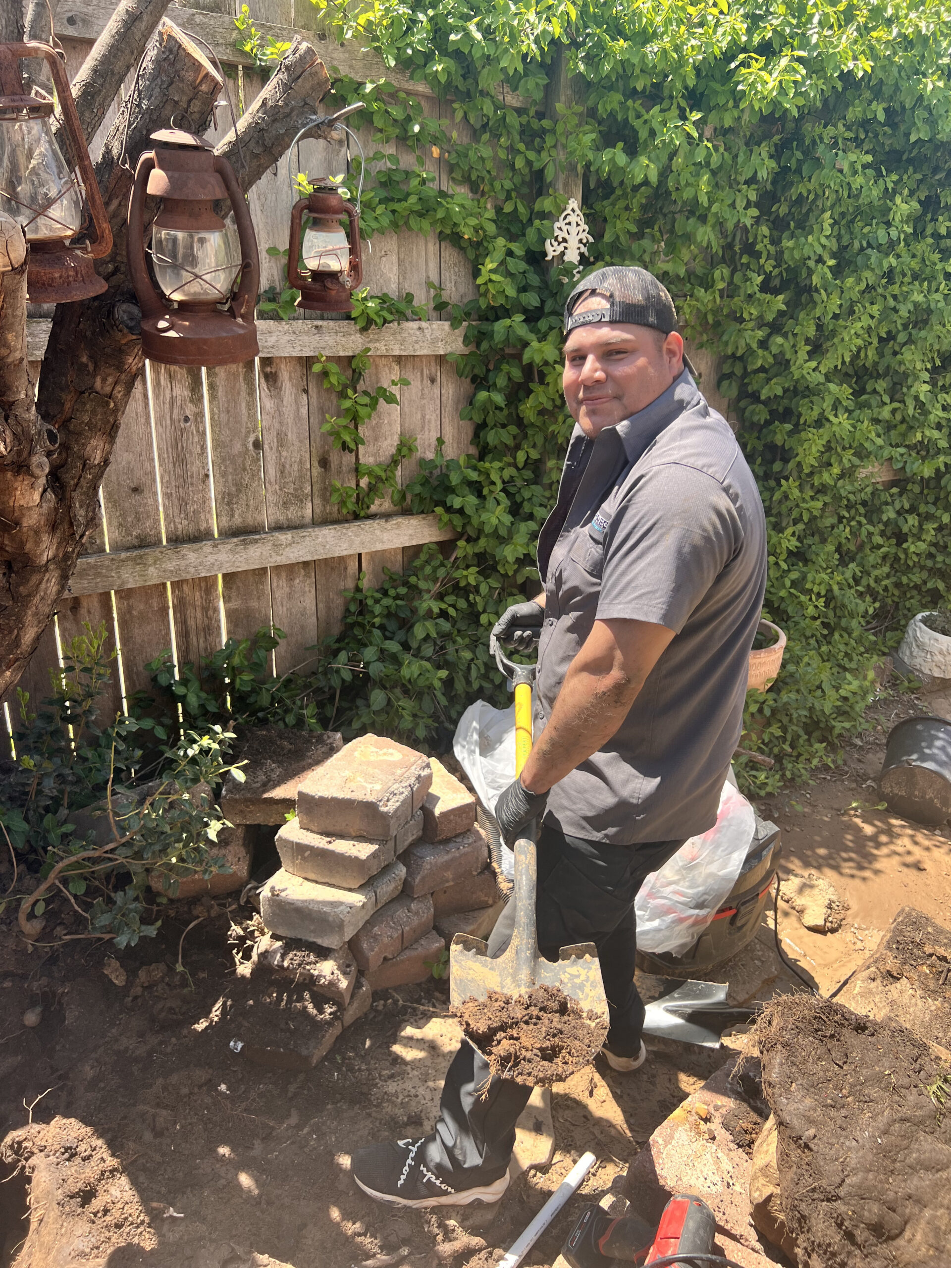 Amped plumber excavating for sewer repair in Oklahoma backyard.