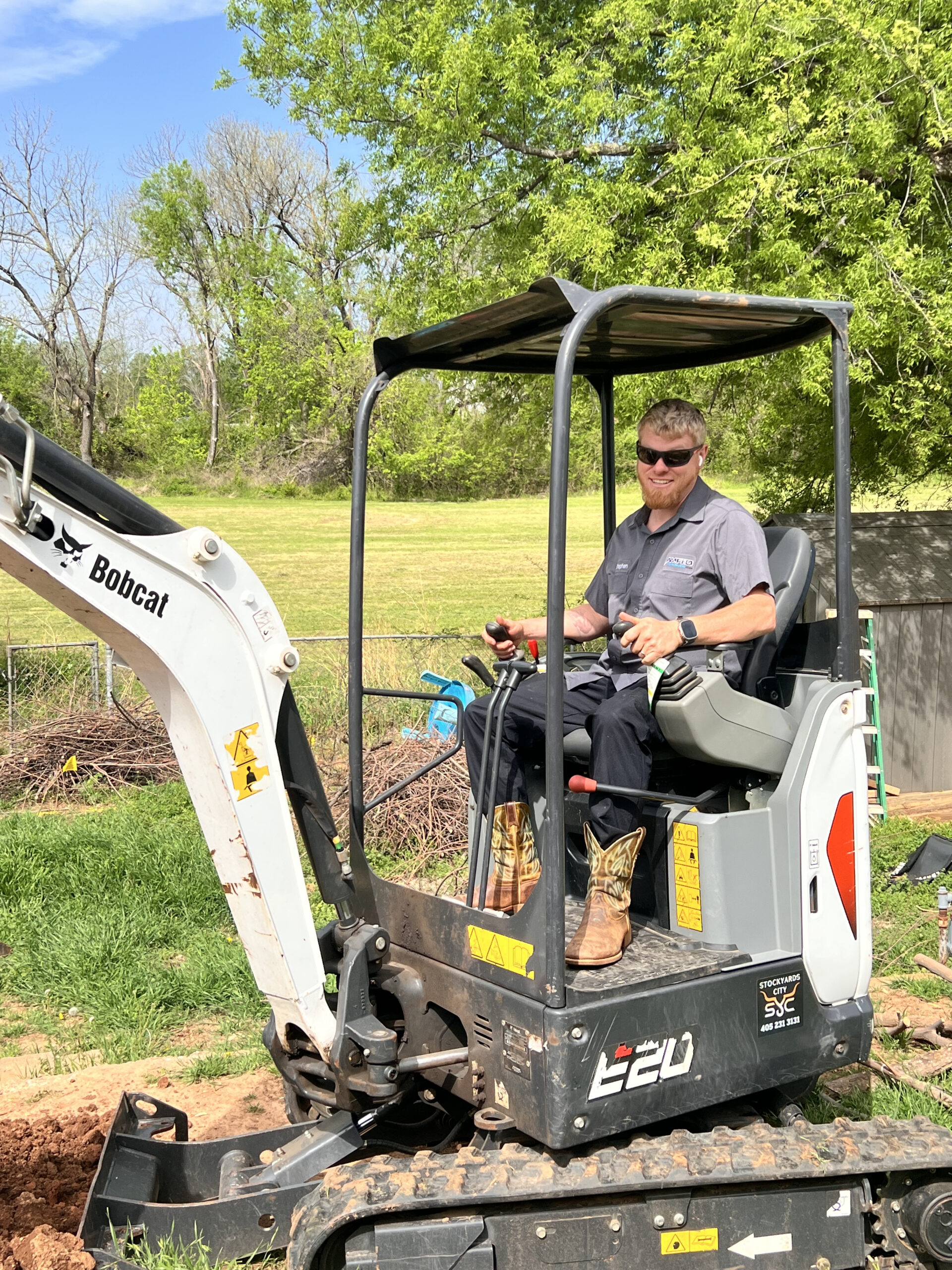 Amped technician using mini excavator for plumbing excavation in Oklahoma.