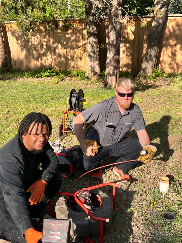 Amped plumbers preparing sewer cleaning equipment in Oklahoma.