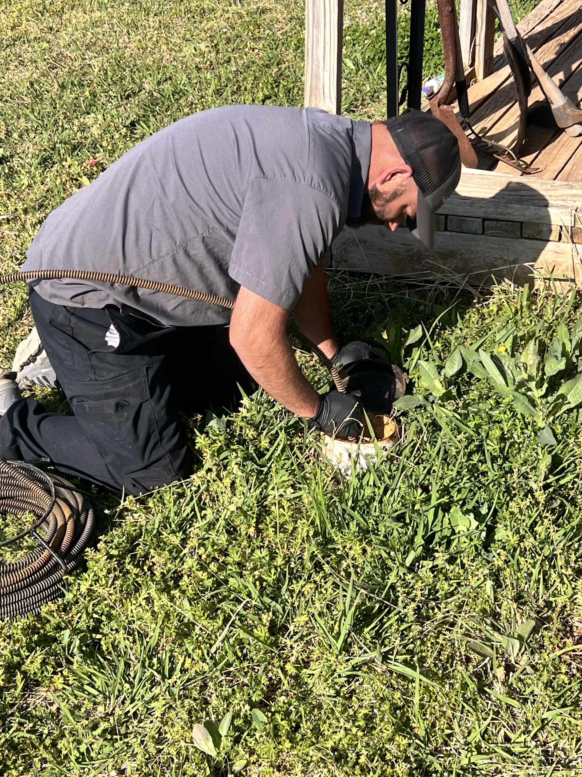 Amped plumber operating drain snake for outdoor clog in Oklahoma.
