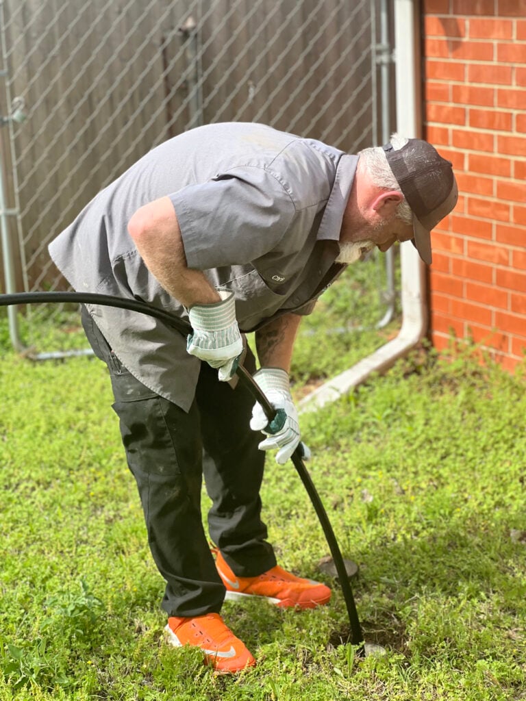 Amped plumber using drain snake for sewer line cleaning in Oklahoma.