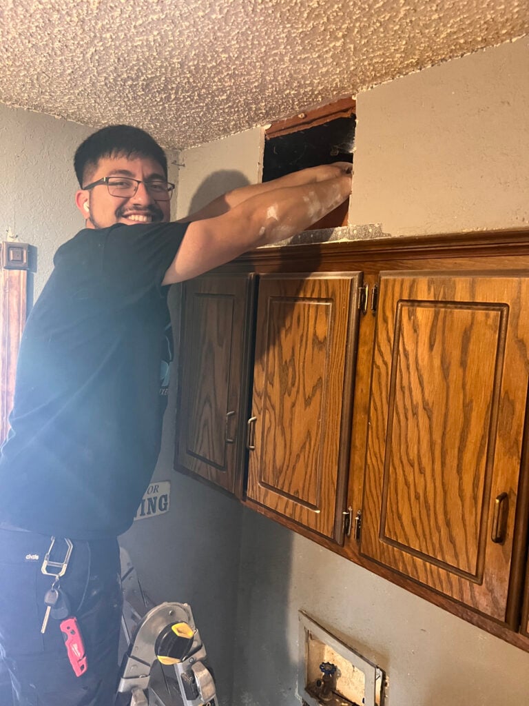 Amped plumber repairing plumbing access inside wall in Oklahoma.