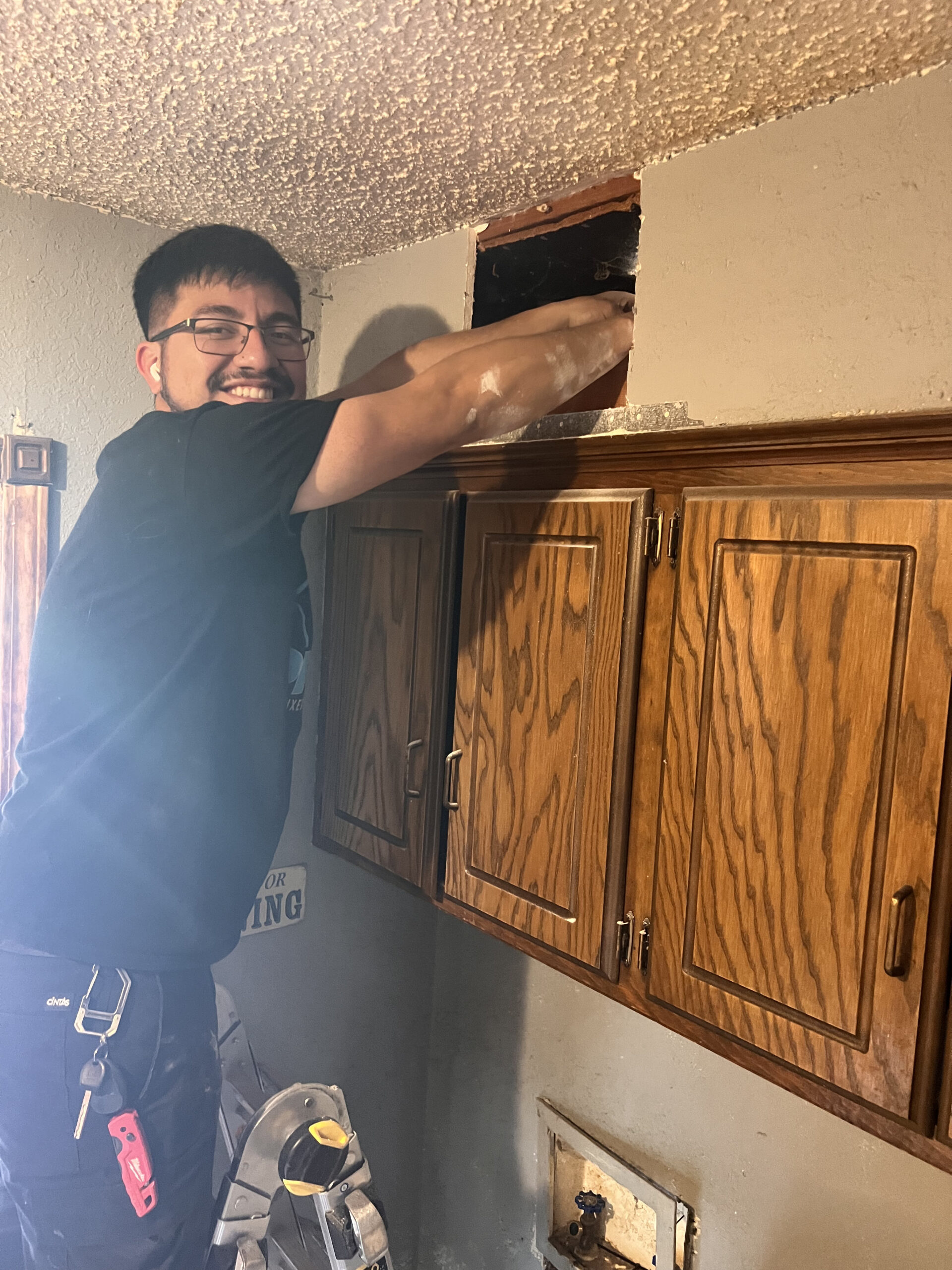 Amped plumber repairing plumbing access inside wall in Oklahoma.