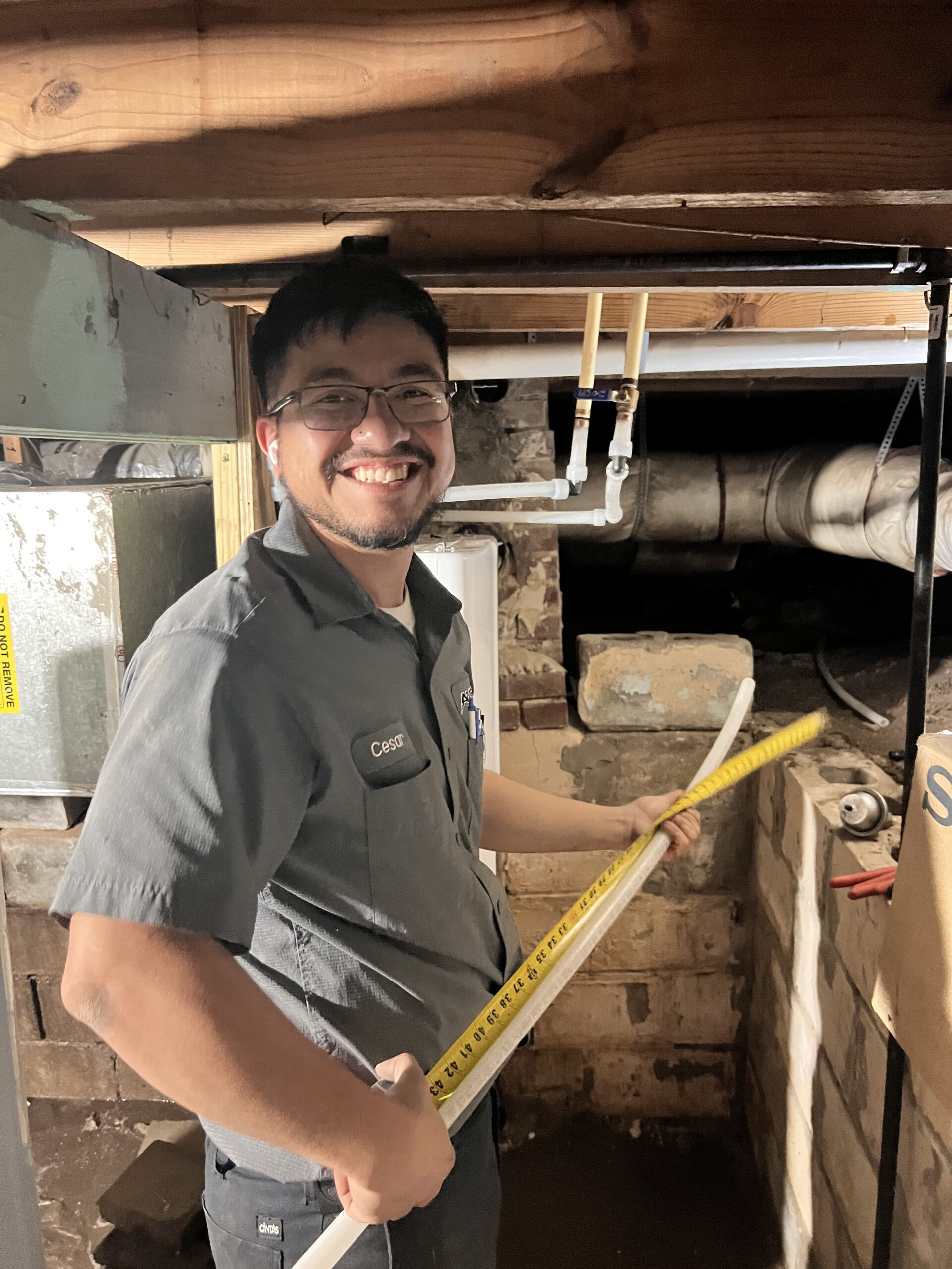 Amped technician inspecting crawl space with tape measure in Oklahoma.