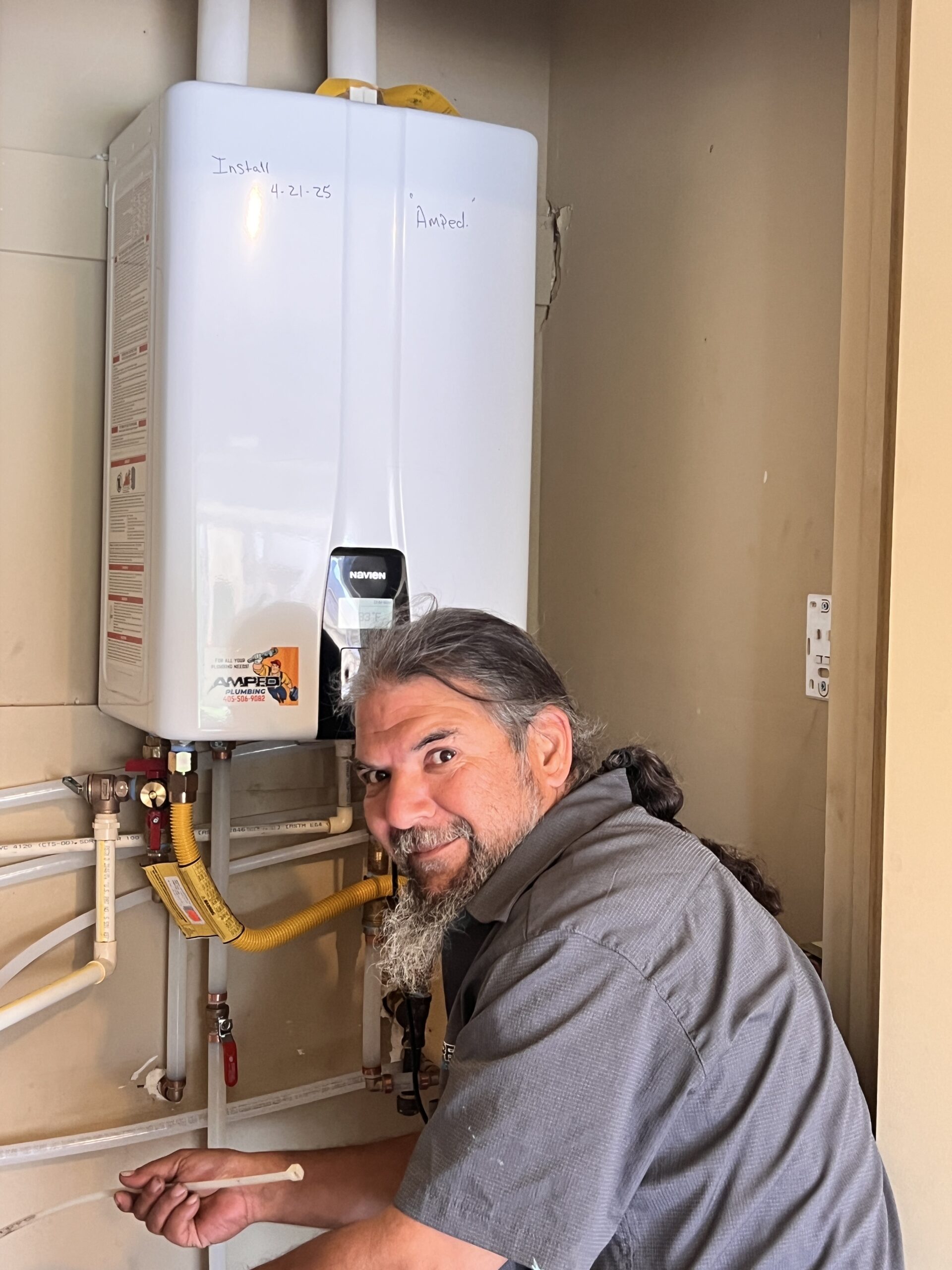 Amped plumber working on tankless water heater in Oklahoma.