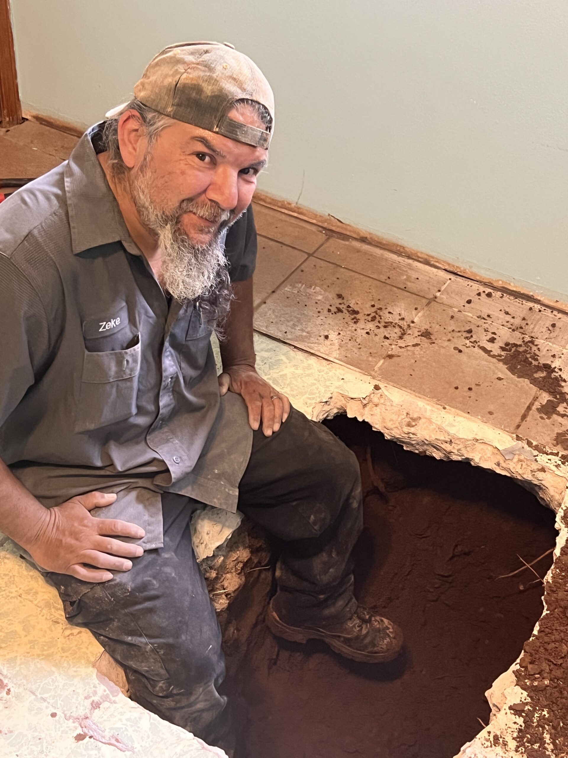 Amped plumber repairing underground plumbing through floor cutout in Oklahoma.