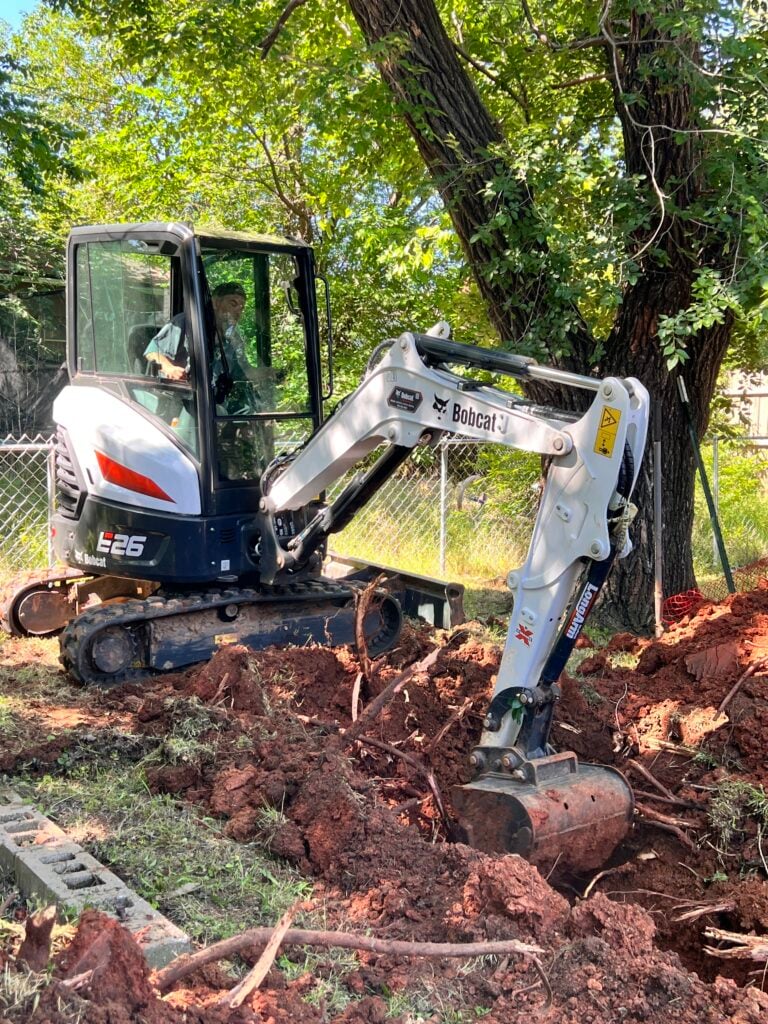 Amped technician operating mini excavator for trenching in Oklahoma.