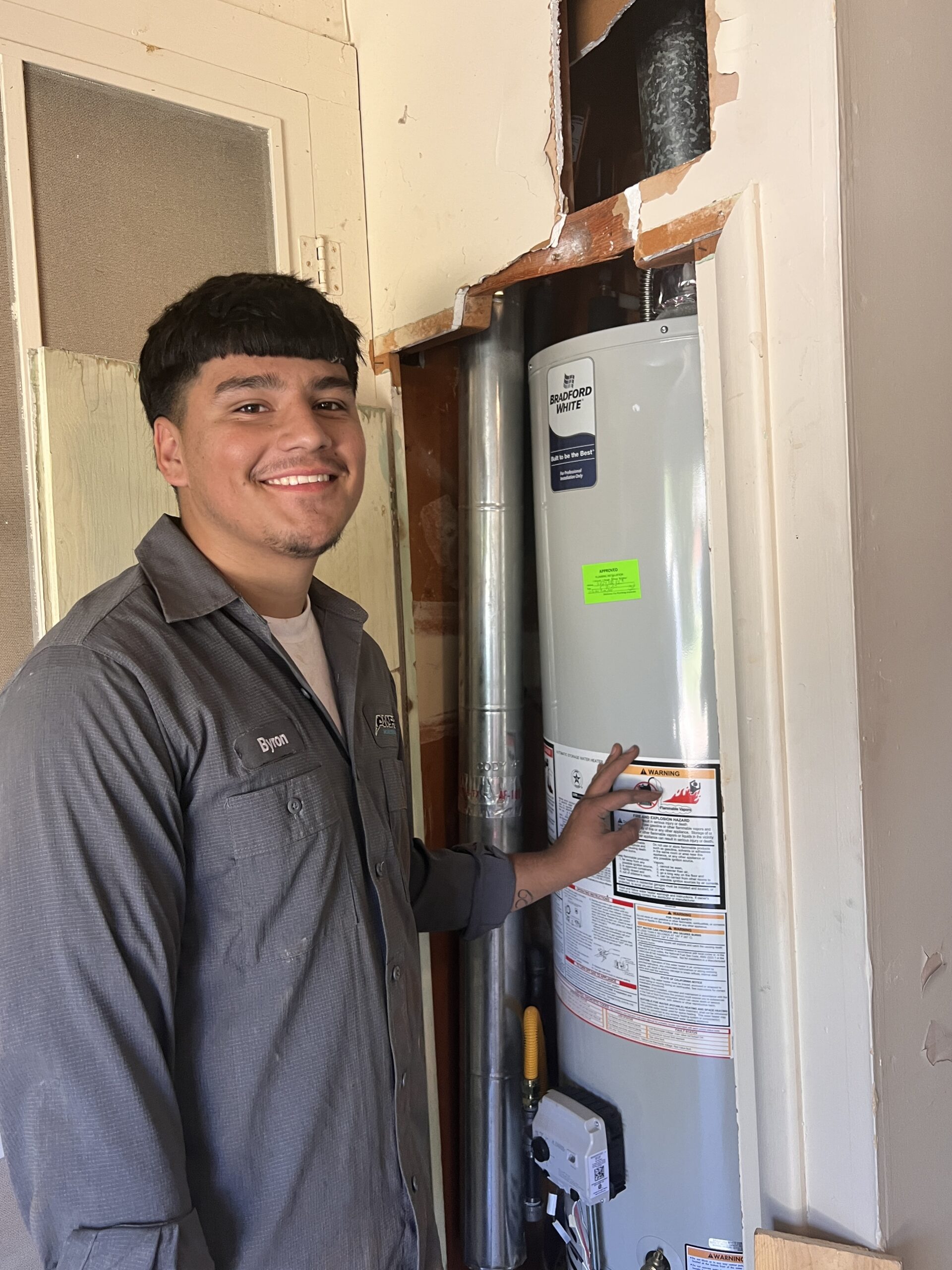 Amped plumber inspecting residential water heater in Oklahoma.