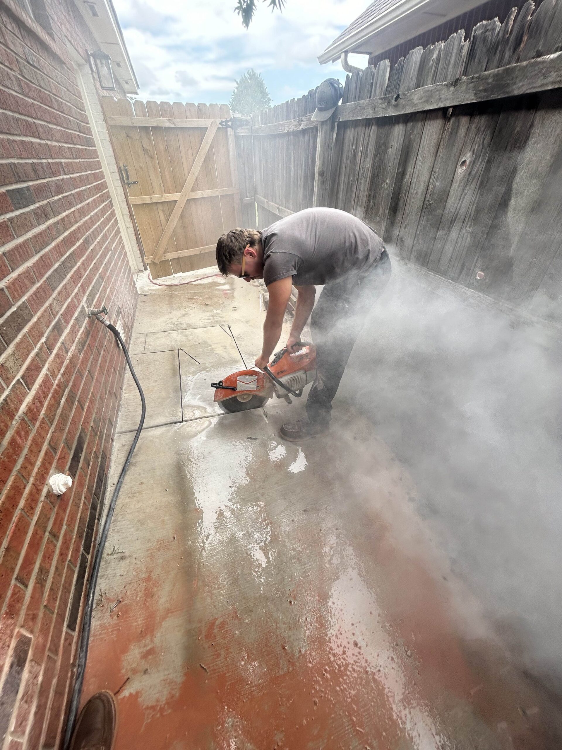 Amped plumber cutting concrete slab for plumbing access in Oklahoma.