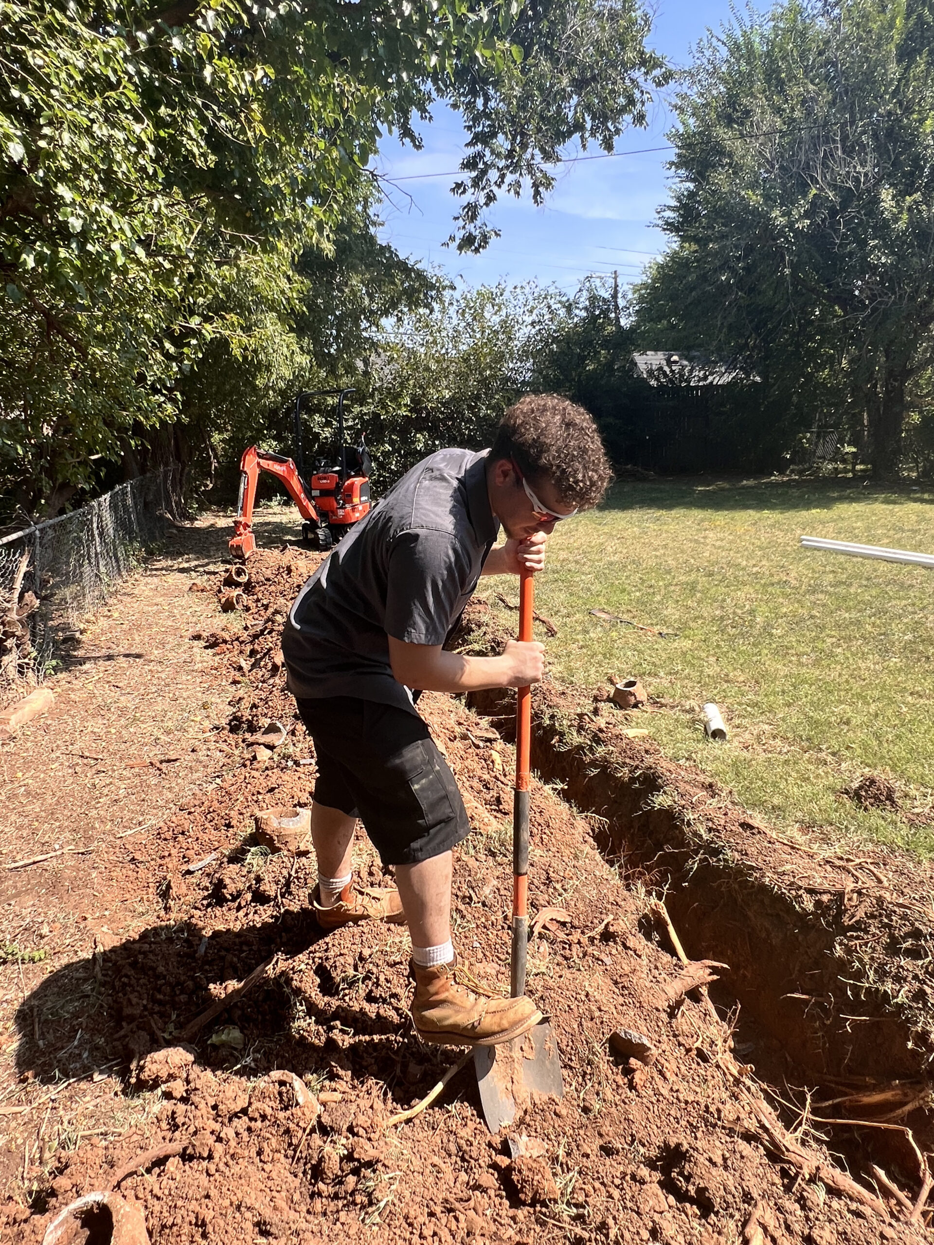 Amped plumber digging trench for underground plumbing in Oklahoma.