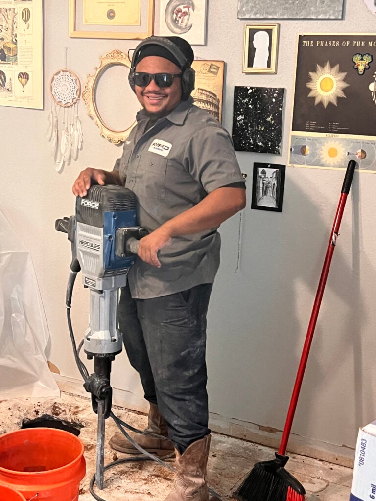 Amped plumber using jackhammer for slab repair in Oklahoma home.