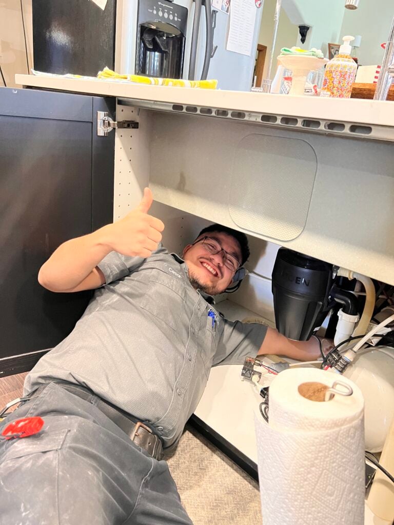Amped technician working under a kitchen sink.