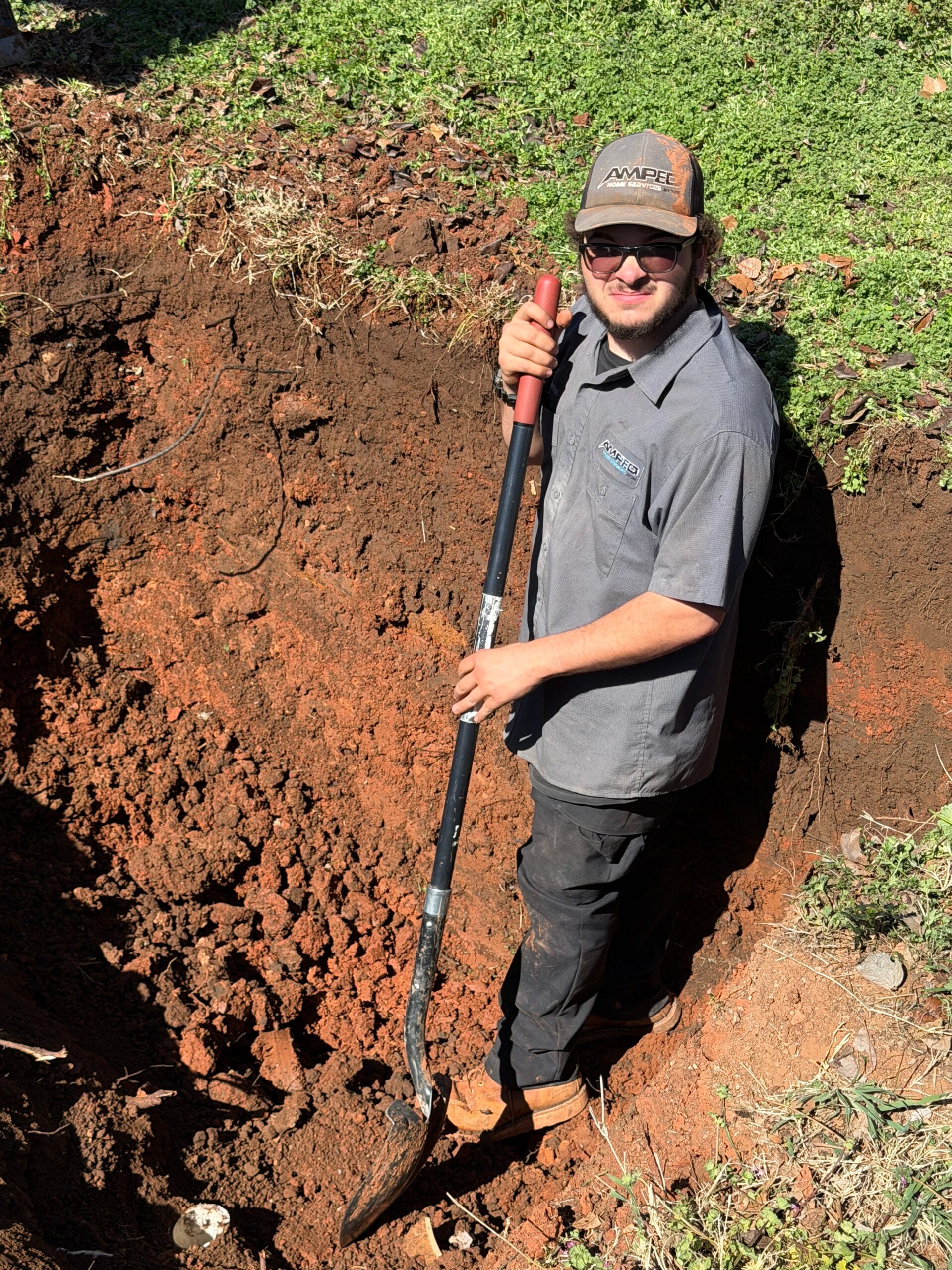 Amped Home Services technician excavating a collapsed sewer line by hand to avoid utility lines. 