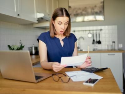 Residential home owner has the appearance of shock as she is looking at her recent water bill. 