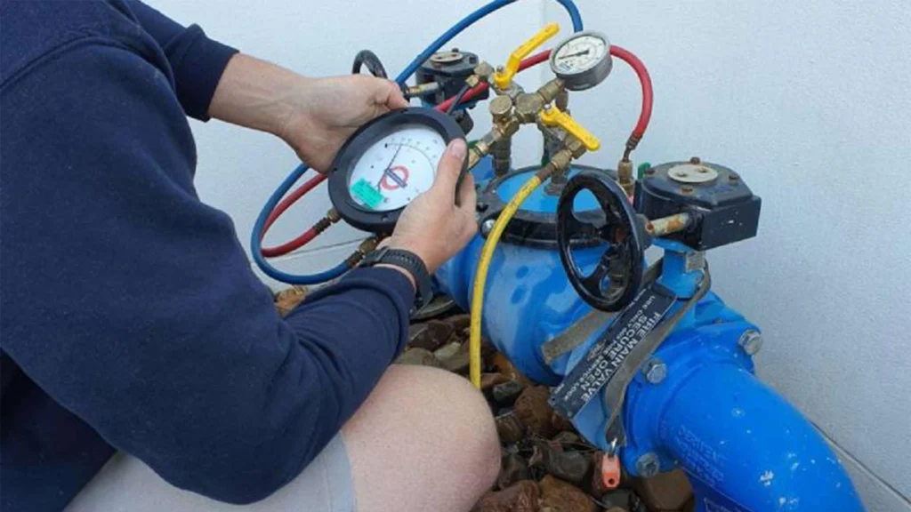 Technician testing a backflow prevention valve with pressure gauges