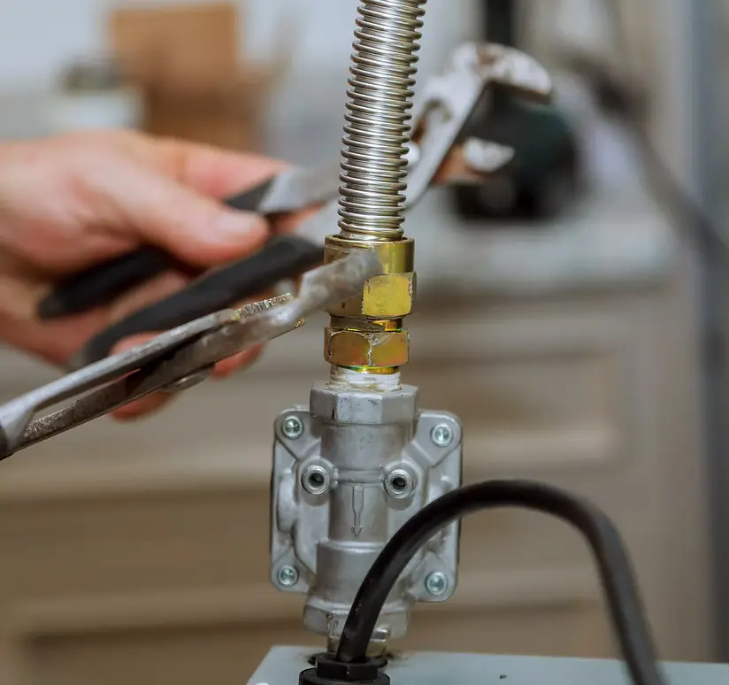 Technician tightening a flexible gas line connection with a wrench