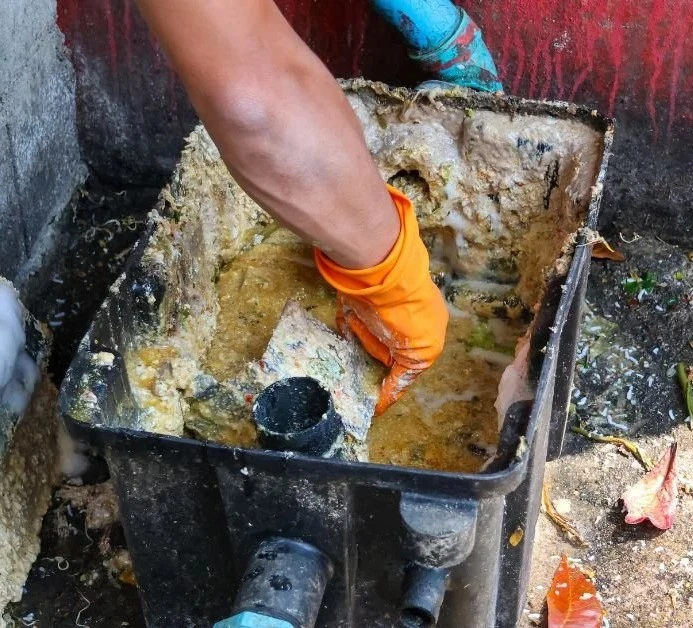 Technician cleaning heavy grease and food waste buildup from a grease trap