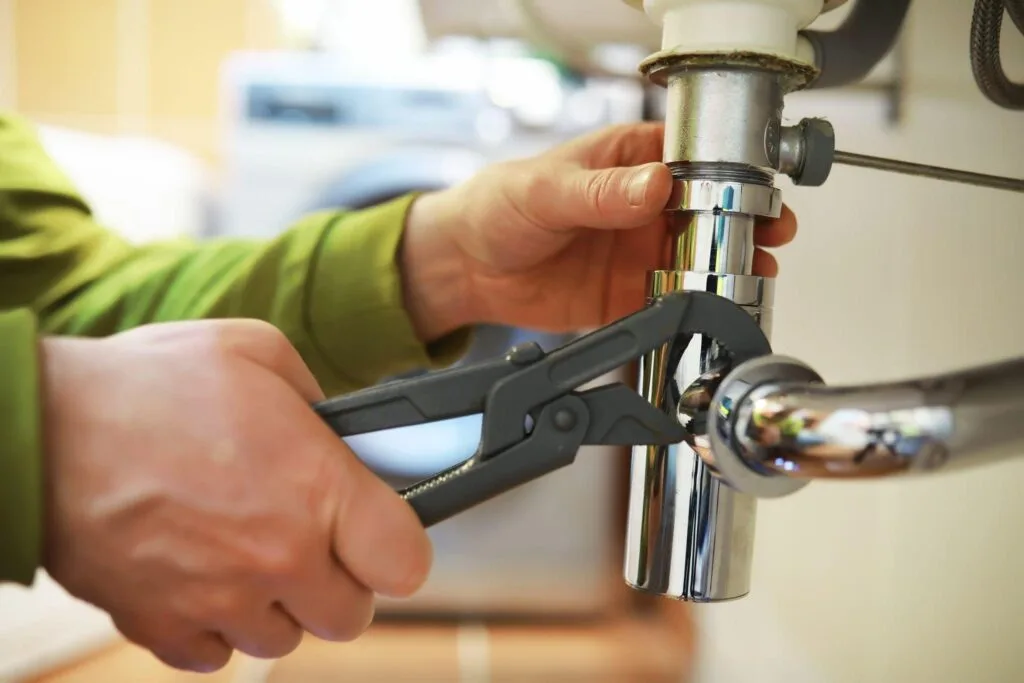 Technician repairing a drain pipe connection beneath a sink