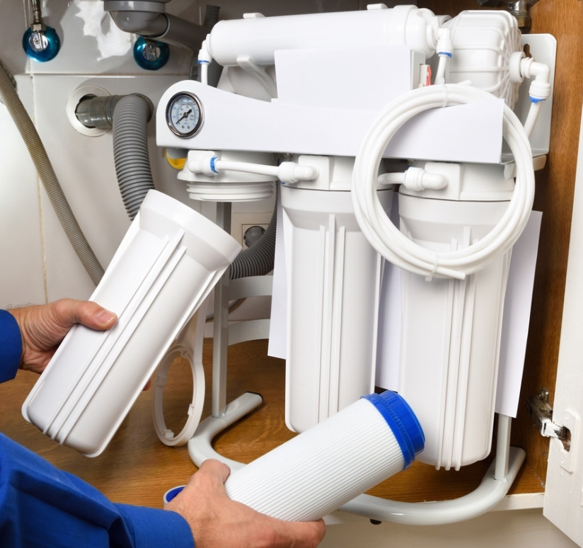 Technician replacing a filter cartridge in an under-sink water filtration system