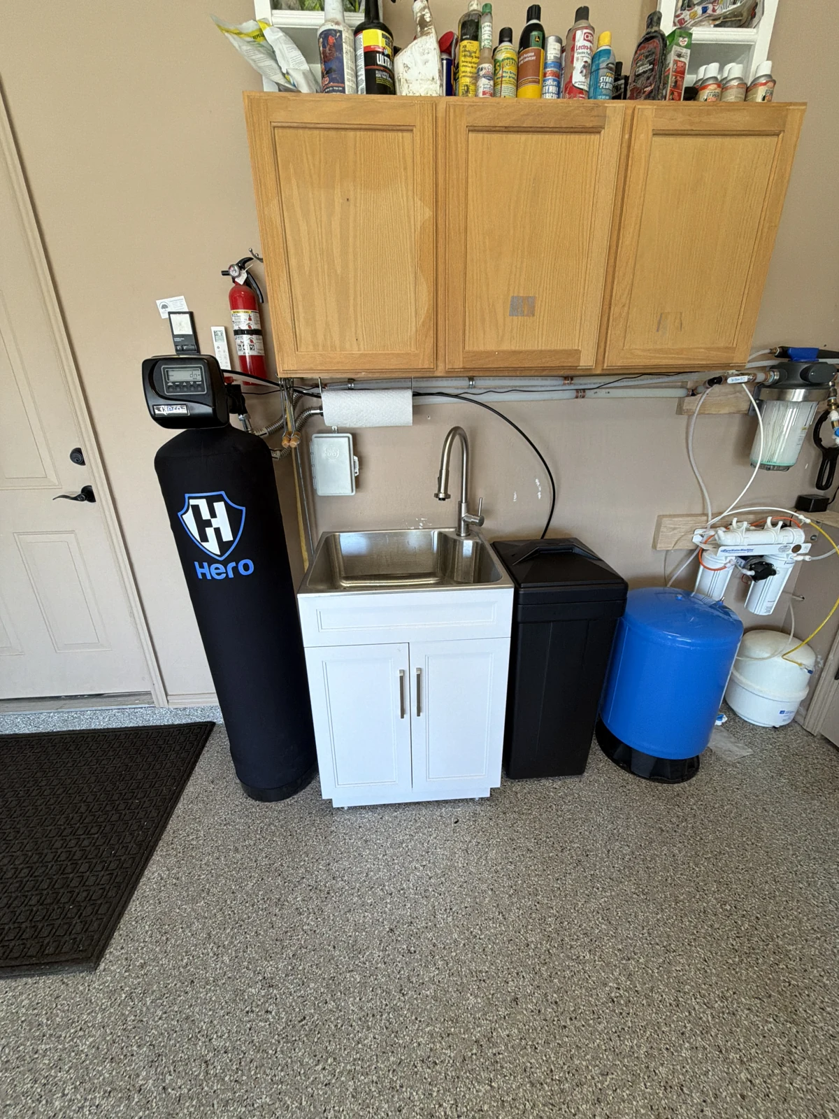 HERO water softener and black brine tank beside a utility sink and wall-mounted filters