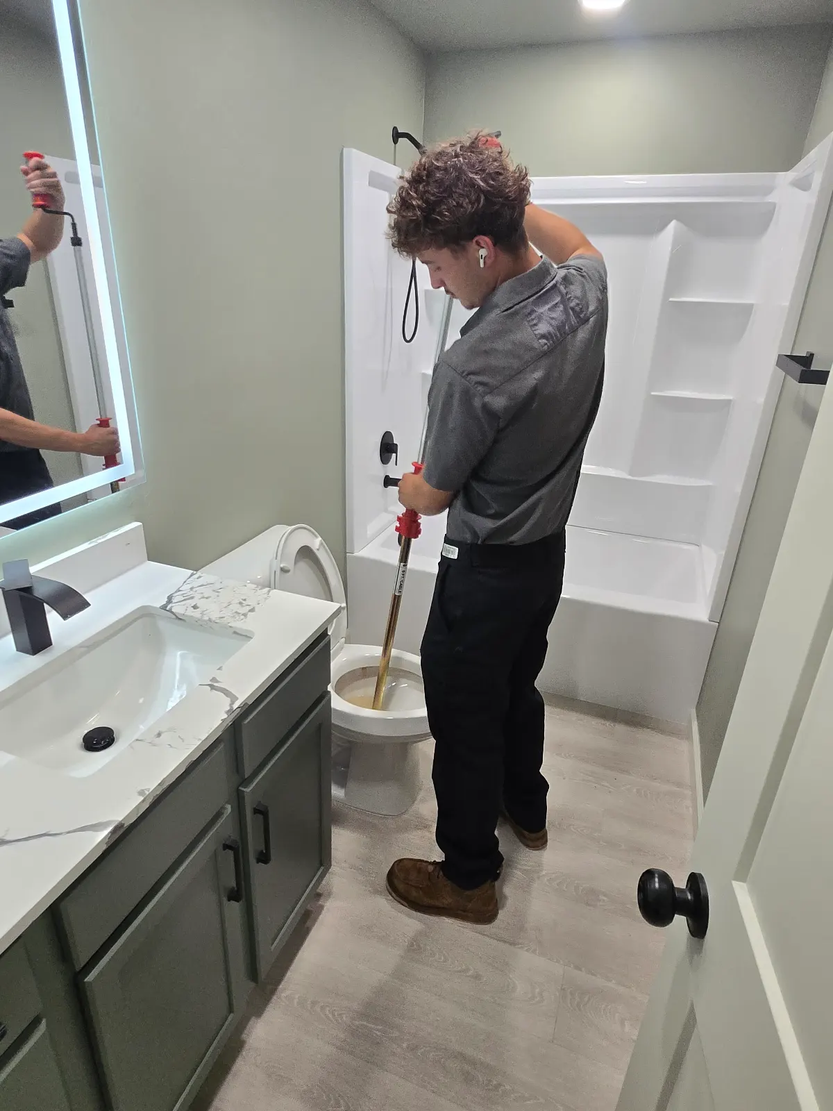 Ashton from Amped using a toilet auger to clear a clogged toilet