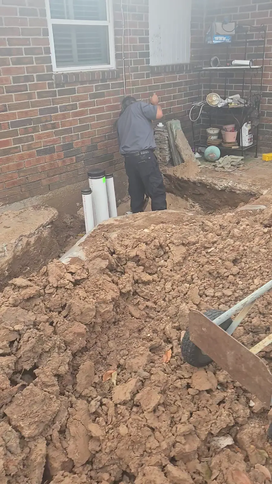Amped technician working beside three cleanouts and an open sewer trench at a patio