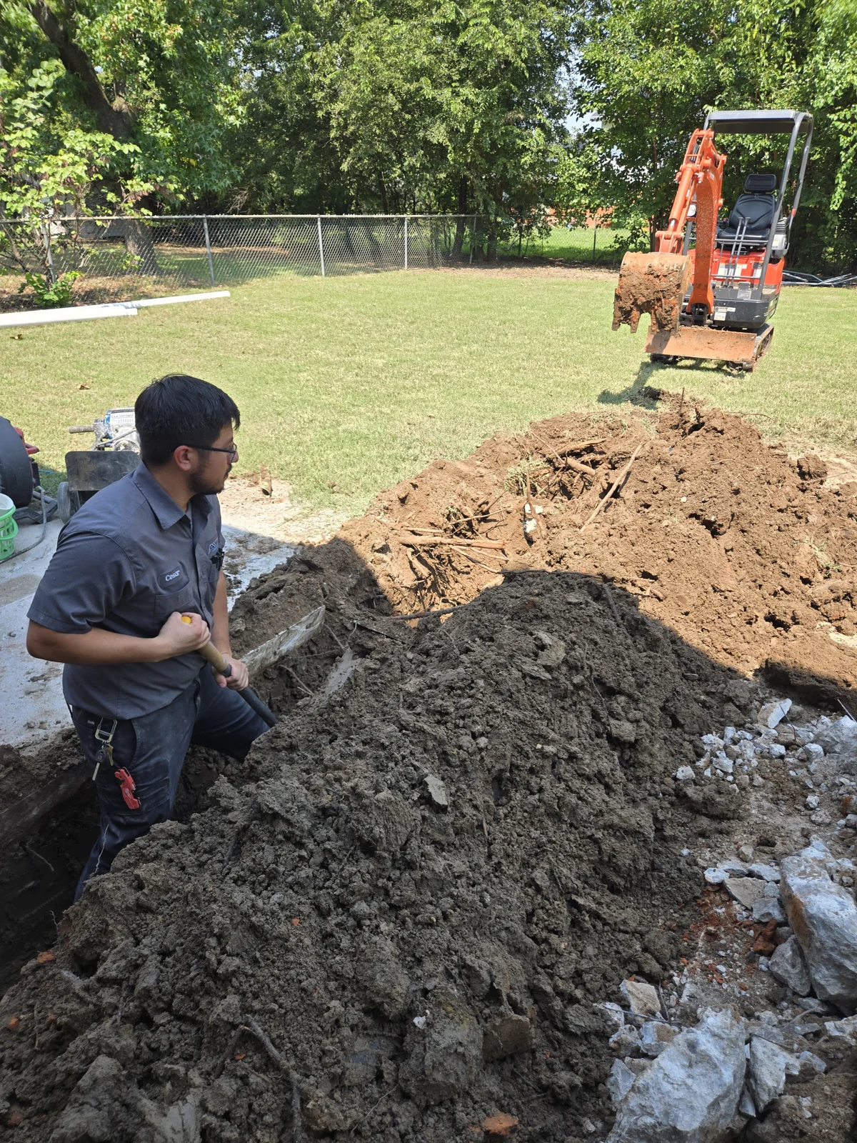 Amped technician excavating a sewer line beside a patio