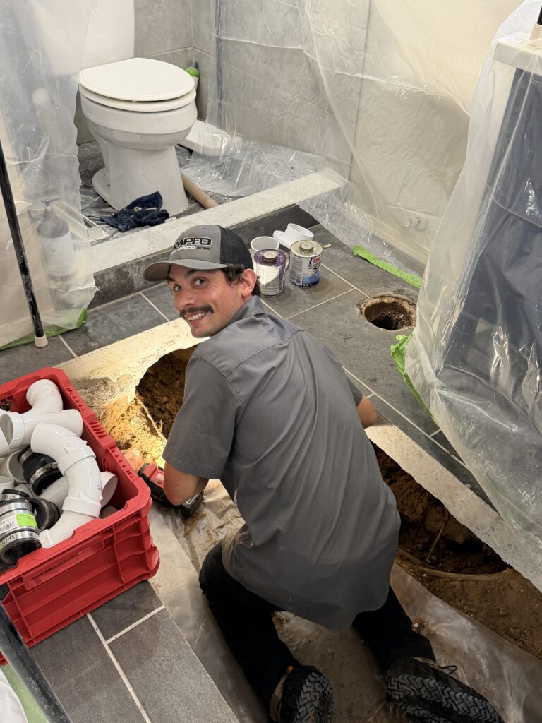 Plumber working on bathroom plumbing and fixture installation.